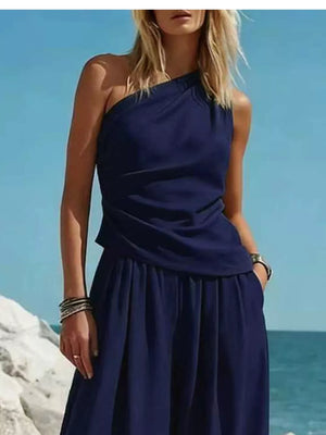 Navy one-shoulder top and wide-leg pants set with draped detail and pockets.