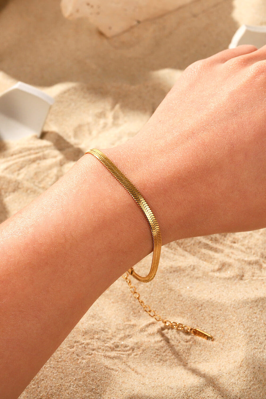 Golden serpent herringbone chain bracelet with adjustable clasp detail.