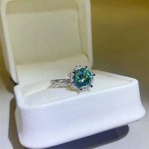 Sterling silver ring with a green moissanite solitaire and halo, set in a white ring box.
