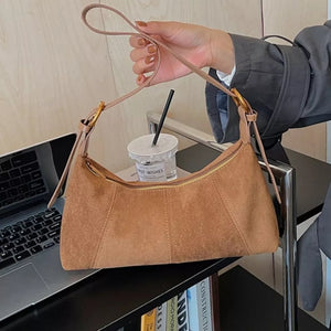 Chic suede crescent shoulder bag in coffee brown with adjustable strap and gold zipper.