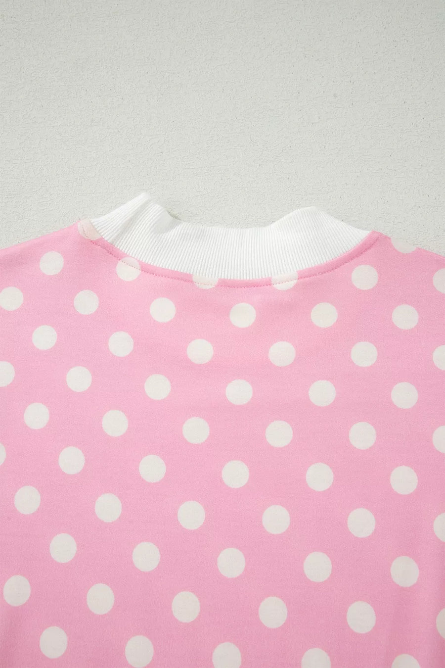 Pink polka dot top with white ribbed mock neck detail