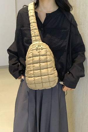 Padded sling bag in coffee brown with quilted pattern and top handle detail.