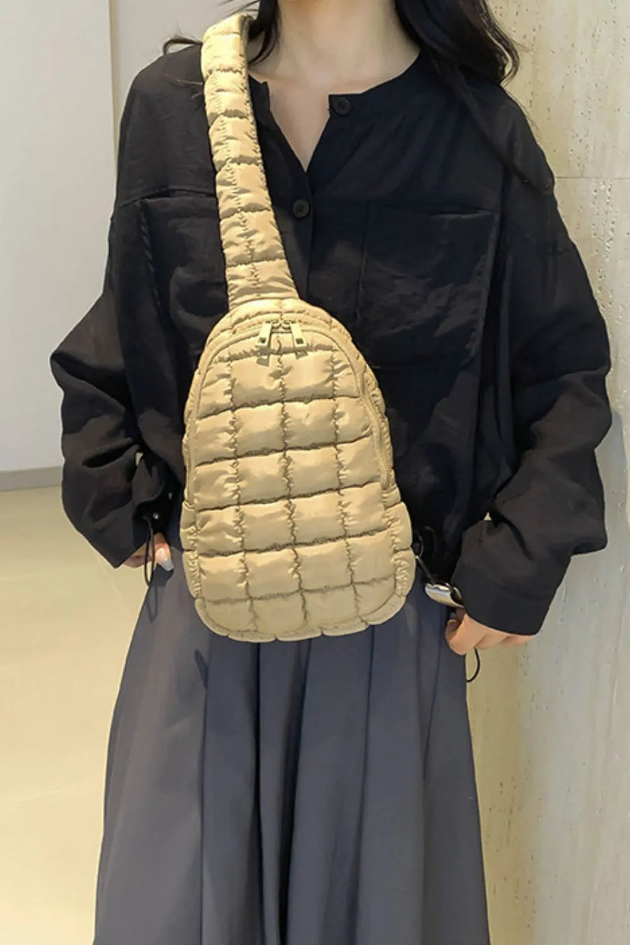 Padded sling bag in coffee brown with quilted pattern and top handle detail.