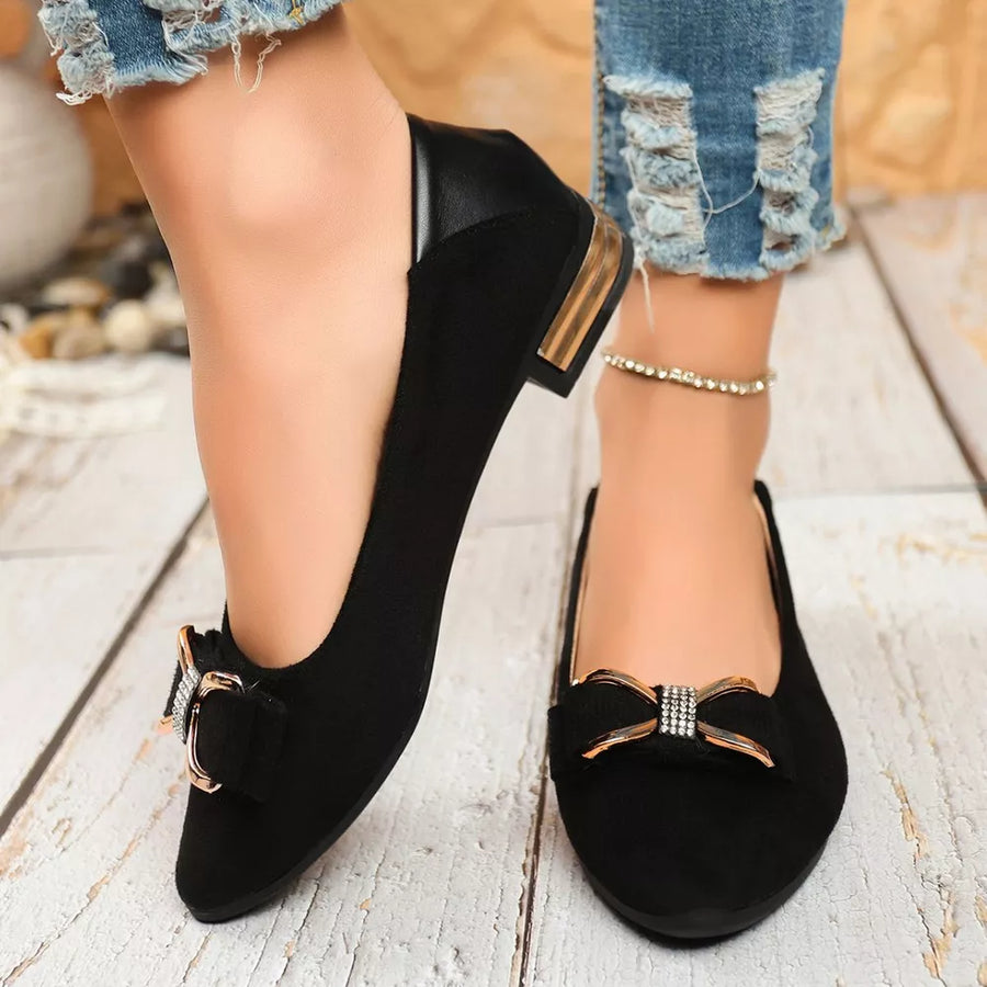 Black pointed-toe block heels with a bow detail and gold accents