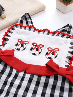 Baby jumpsuit with gingham pattern, soccer ball embroidery, and red bows.