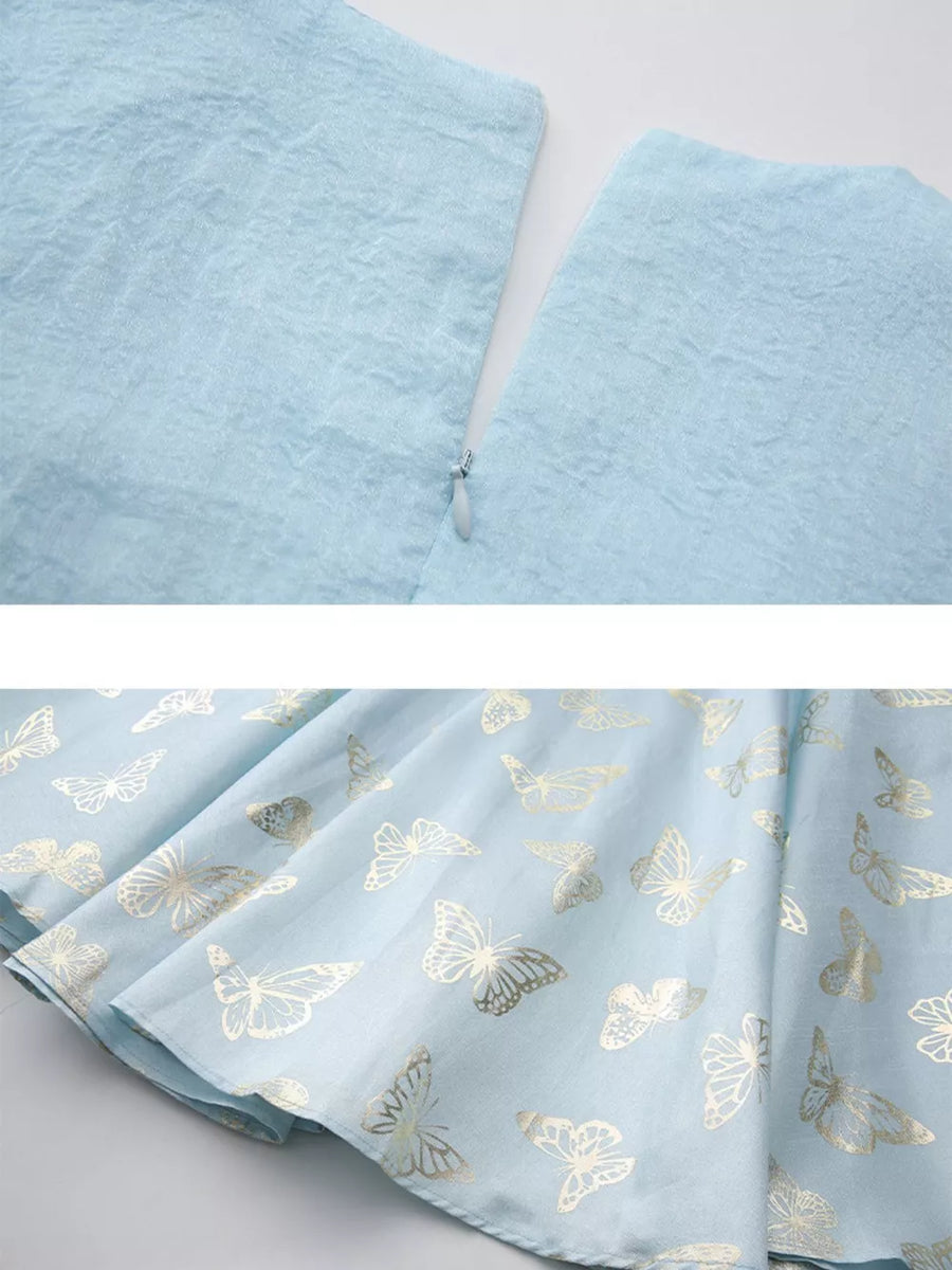 Light blue midi dress with gold butterfly print and cinched waist detail.