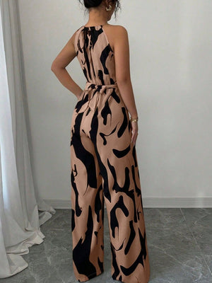 Elegant wide-leg jumpsuit in tan with abstract black print, halter neck, and tie waist.