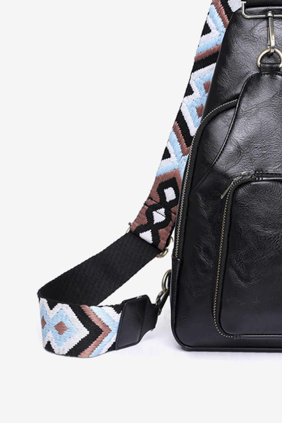 Black PU sling bag with a black strap featuring a geometric embroidered pattern in white, blue, and brown.