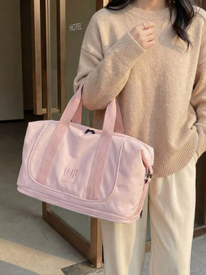 Pink duffel bag with embroidered logo and dual handles, styled with a beige sweater.
