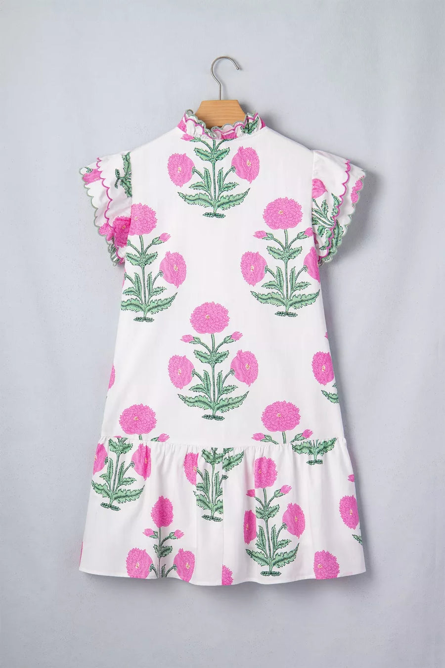 White mini dress with pink floral print, ruffled neckline, and scalloped flutter sleeves.
