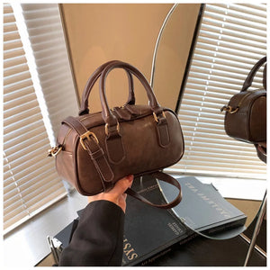 Chic mini barrel crossbody bag in brown faux leather with gold hardware and adjustable strap.