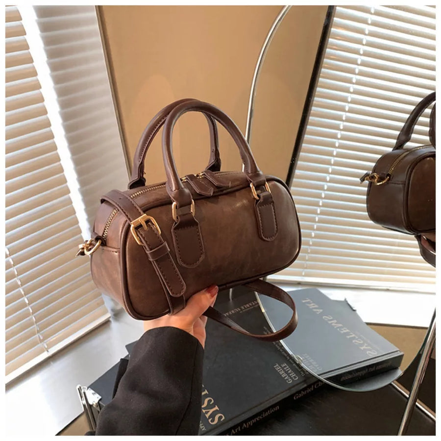 Chic mini barrel crossbody bag in brown faux leather with gold hardware and adjustable strap.
