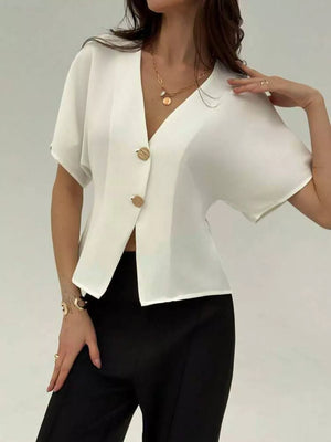 White asymmetrical V-neck buttoned shirt with short sleeves and gold buttons.