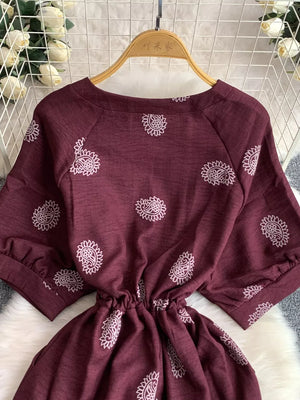 Burgundy paisley print drawstring jumpsuit with short sleeves and cinched waist.