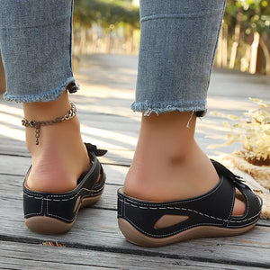 Black floral embellished mid-wedge sandals with white stitching and cut-out details.