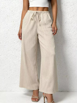 Relaxed beige cotton wide-leg pants with adjustable drawstring waist and pockets.