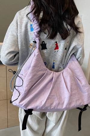 Lilac gathered crescent shoulder bag with rope strap detail and black buckle accents.