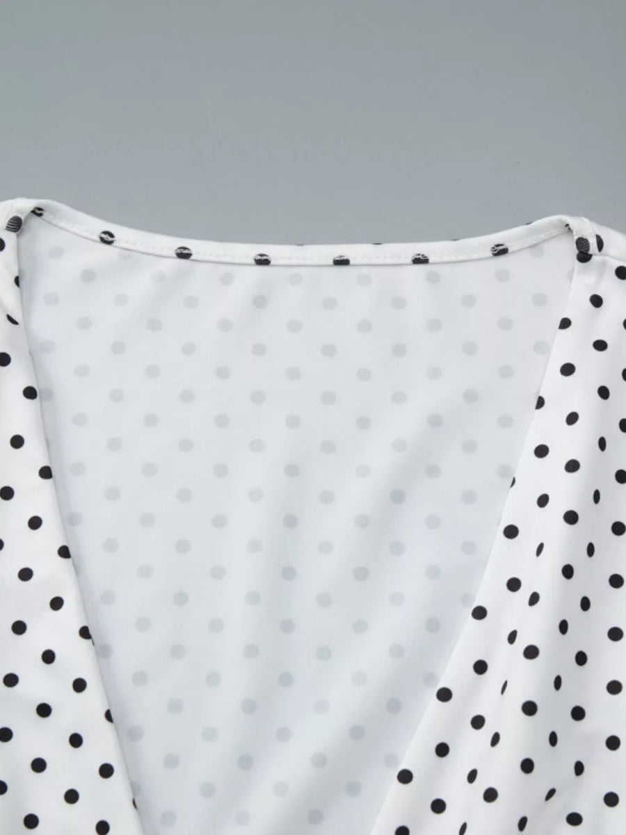 White polka dot ruched t-shirt with a v-neckline and short sleeves.