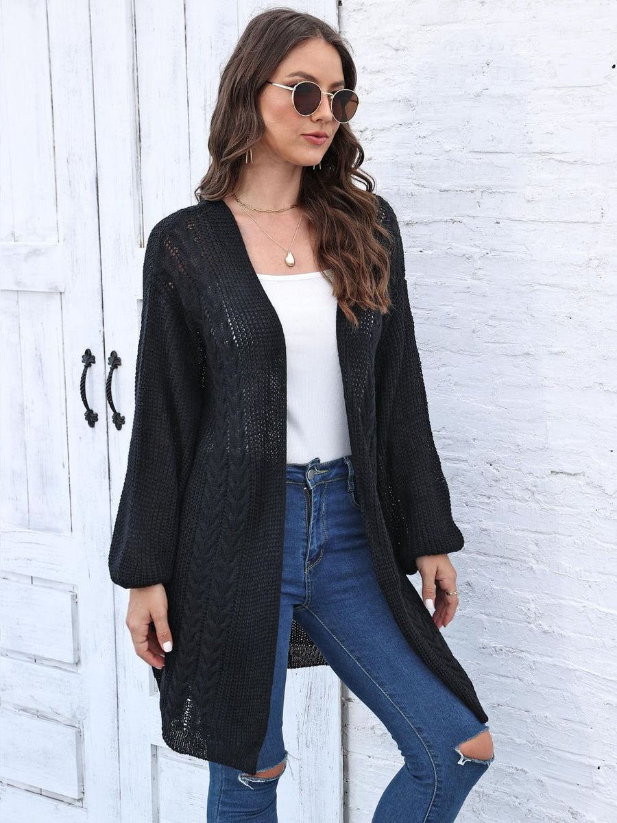 Black cable knit cocoon cardigan with V-neck and long sleeves.