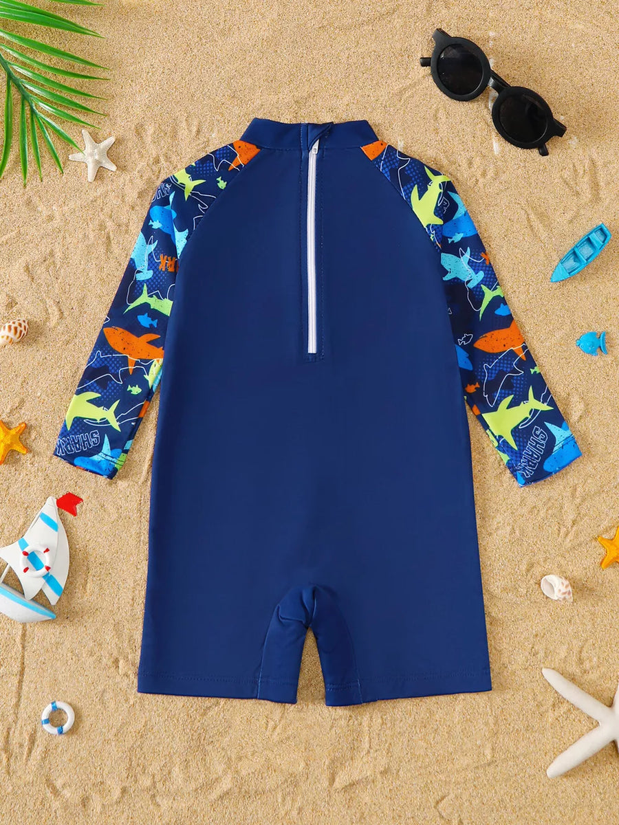 Navy baby rash guard swimsuit with shark print on sleeves and collar.