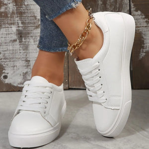 White leather-look platform sneakers with lace-up closure and gold chain anklet.
