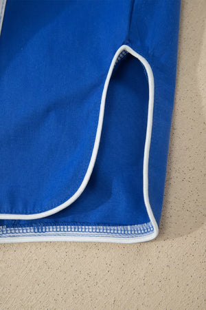 Blue maternity cropped pants with white piping detail on the hem and side slit.