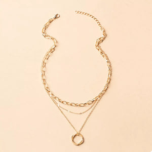 Gold layered necklace with three delicate chains and a geometric pendant.