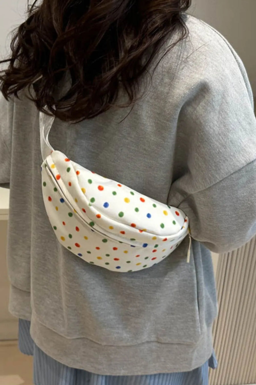 White belt bag with colorful polka dots, worn crossbody.