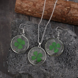 Pressed clover resin jewelry set with green four-leaf clovers in round pendants and earrings.