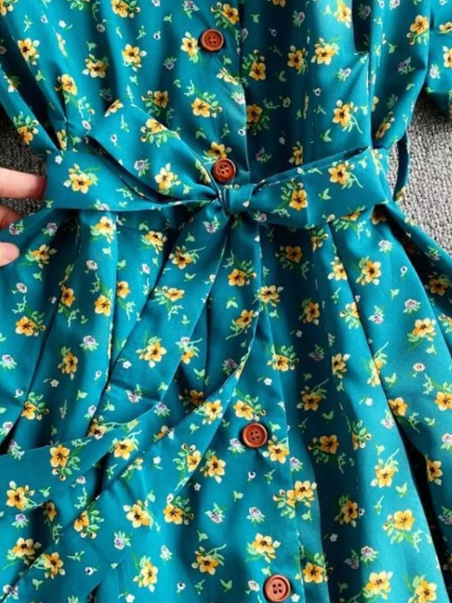 Light blue floral midi dress with V-neck, button front, and belted waist.