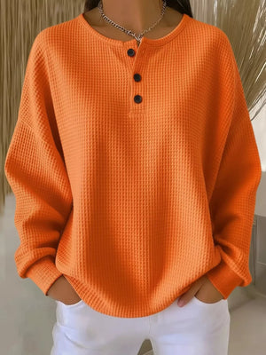 Orange waffle knit button detail casual top with crew neck and long sleeves.