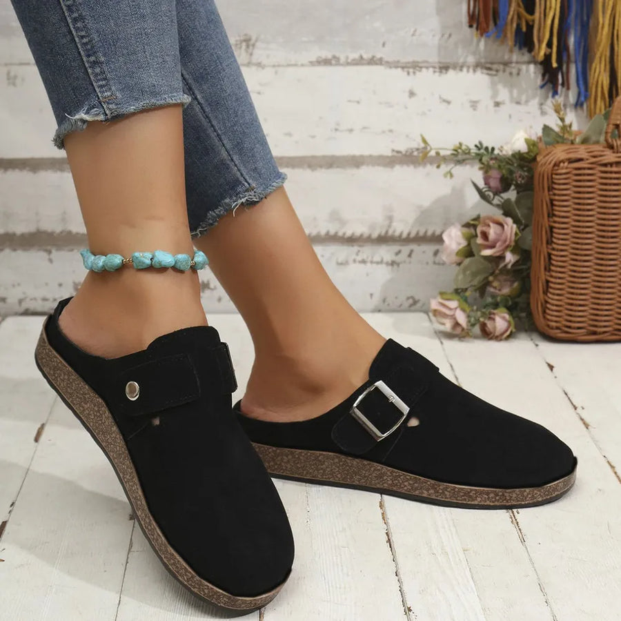 Black suede mule flats with buckle detail and cork sole.