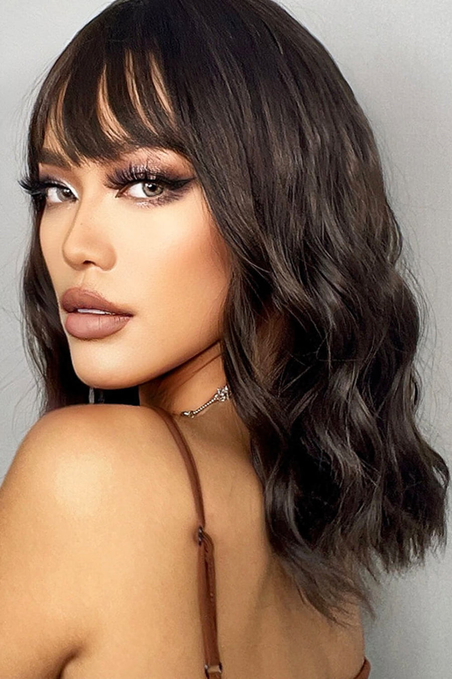 Textured black bob wig with fringe and subtle highlights, styled with soft waves.