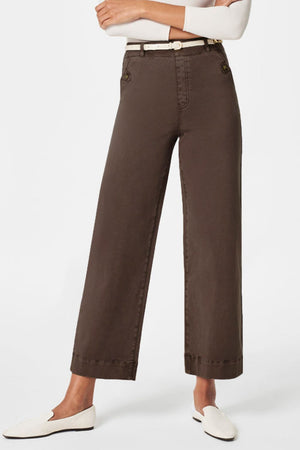 Wide-leg utility denim trousers in tan with button details and a white belt.