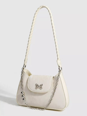 White shoulder bag with braided strap, butterfly charm, and silver chain detail.