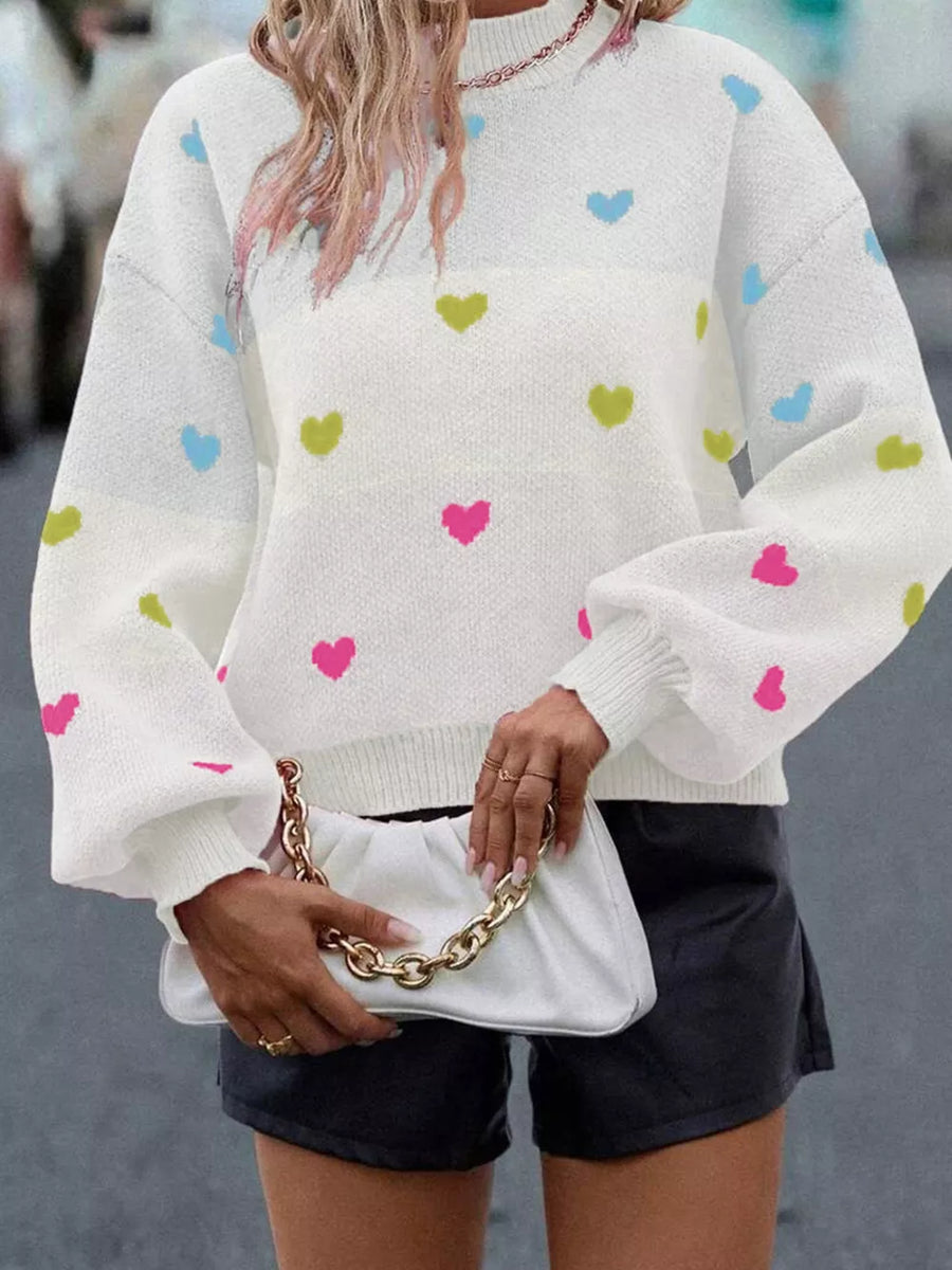 White crew neck sweater with colorful heart pattern and balloon sleeves.