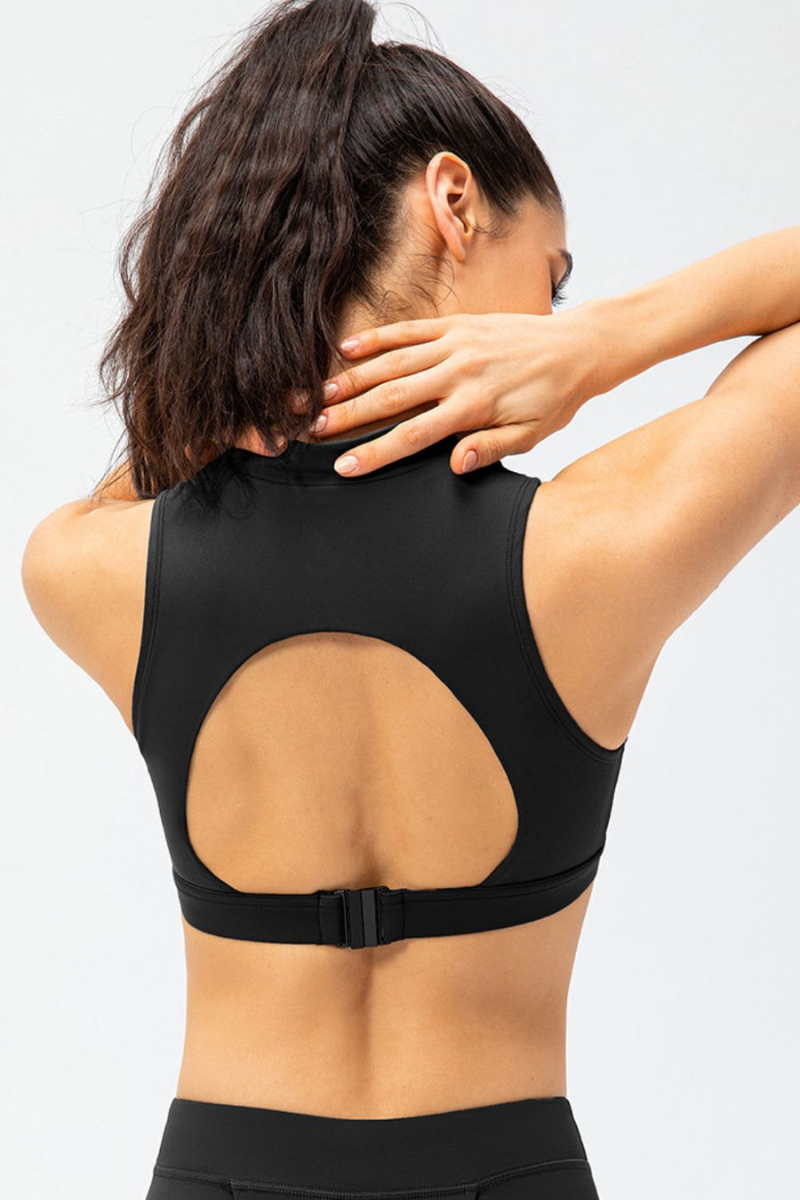 Black high-neck zip-front active crop top with back cutout and adjustable strap.