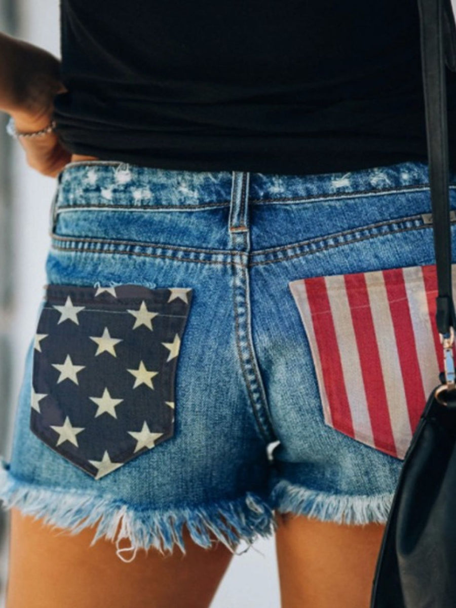 Blue denim shorts with American flag print pockets and frayed hem
