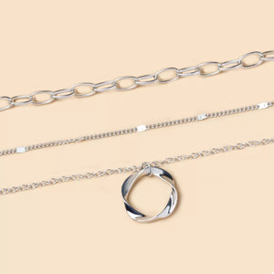 Silver layered necklace with a twisted circle pendant and delicate chains.