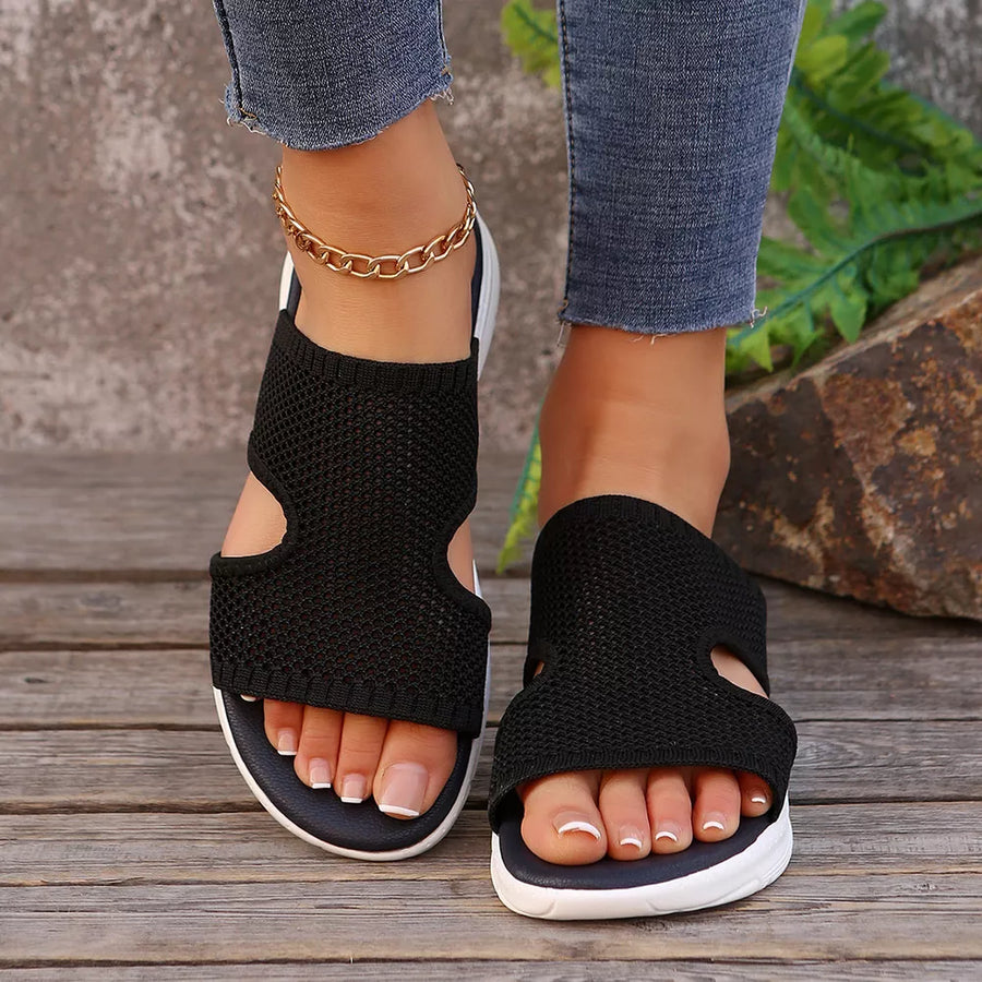 Black mesh open-toe sandals with cutouts and a white sole.