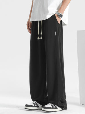 Men's black loose fit sweatpants with drawstring and side tag detail.