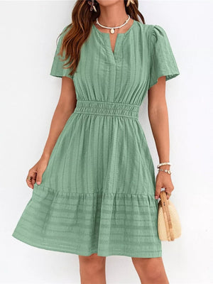 Light green textured V-neck tiered dress with smocked waist and short sleeves.