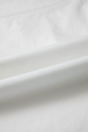 White cotton shirt with subtle pleating and ruffled details.