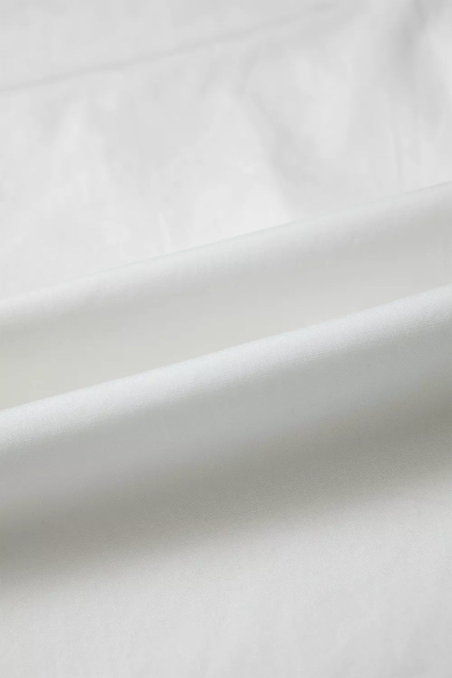 White cotton shirt with subtle pleating and ruffled details.