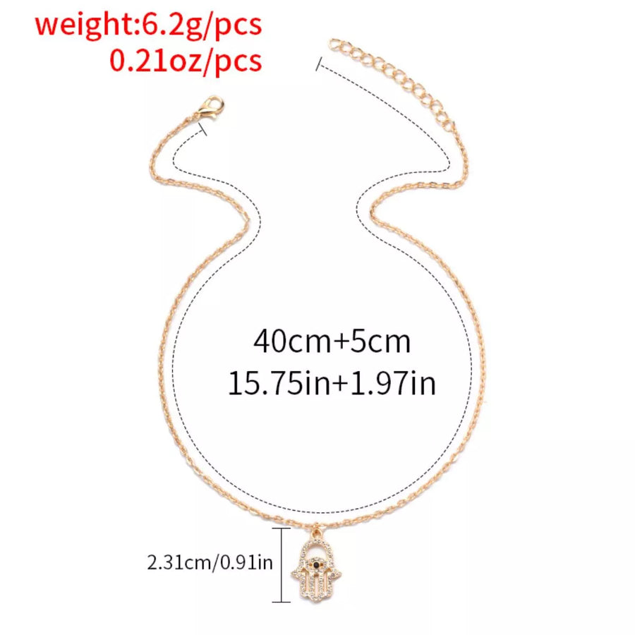 Gold evil eye hamsa pendant necklace with rhinestones and adjustable chain.
