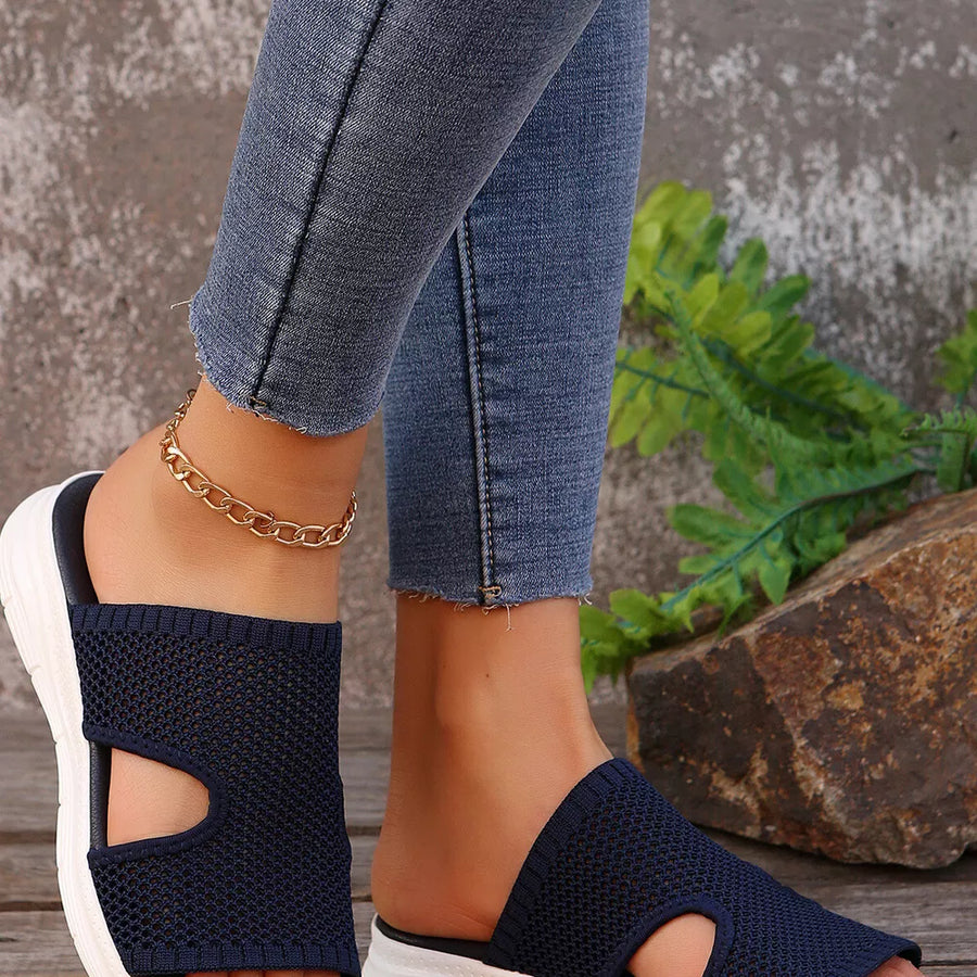 Dark blue mesh slip-on sandals with open toe and white sole, styled with jeans and gold anklet.