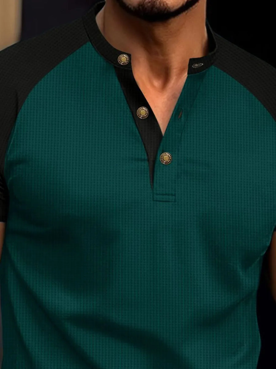Dark green waffle knit henley polo shirt with black raglan sleeves and gold button detail.