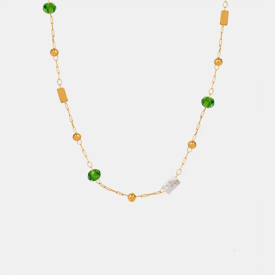 Gold layered necklace with green beads, gold spheres, and clear rectangular charms.