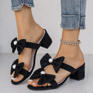 Black bow block heel mules with pearl embellishments.