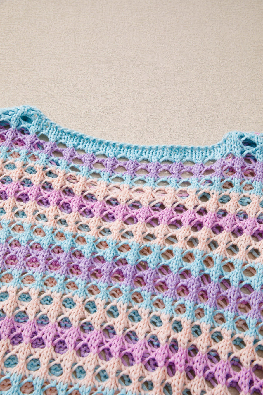 Pastel crochet beach cover-up with a diamond net pattern in lavender, pink, and blue stripes.